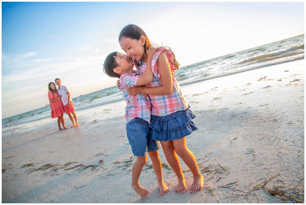 brother and sister whispering to each other on the beach