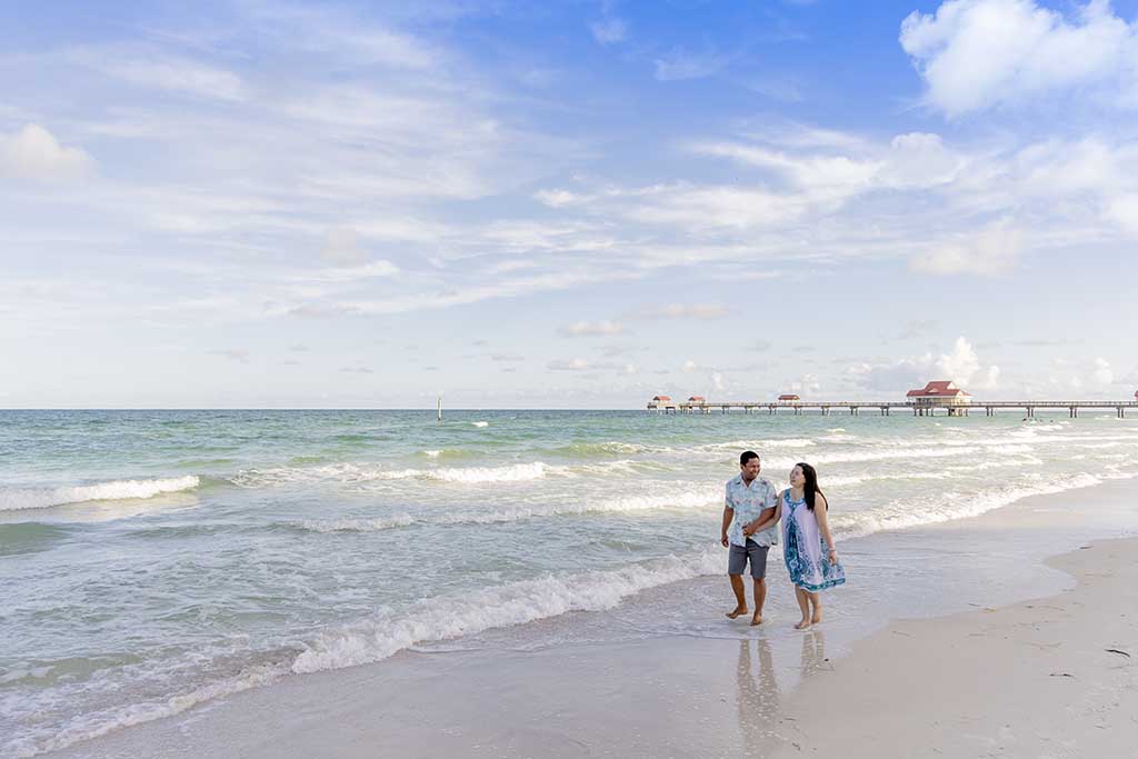 couple holding hands walking down beach