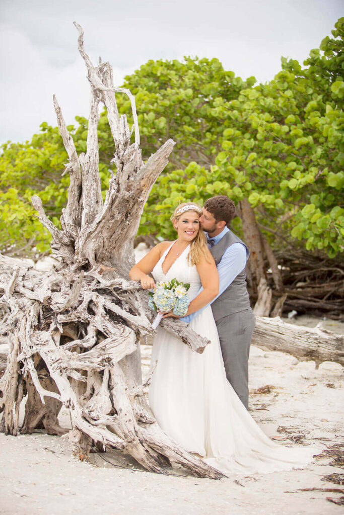 bride and groom kissing by driftwood