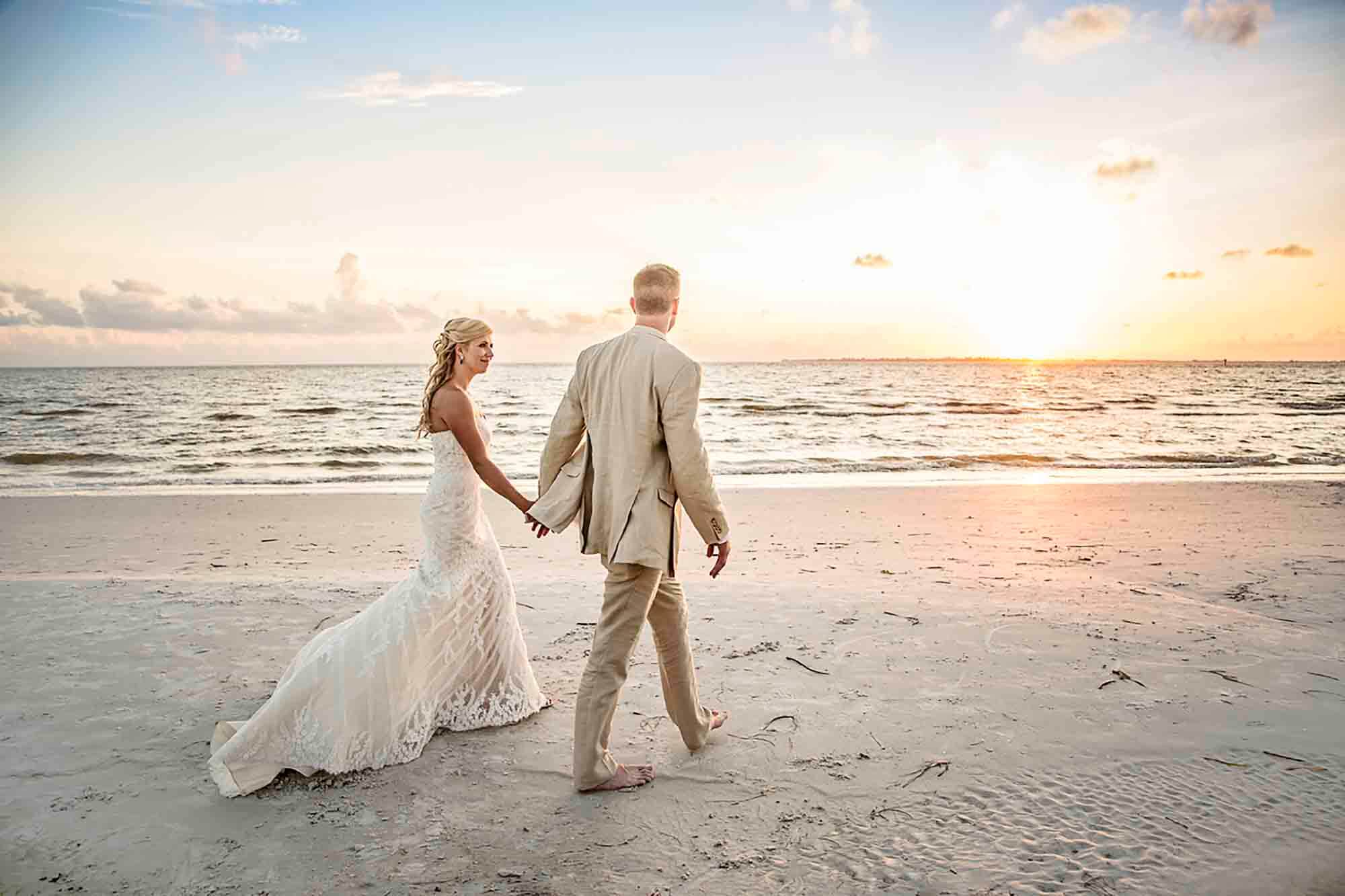 bride and groom holding hands on beach at sunset- wedding photographer tampa fl