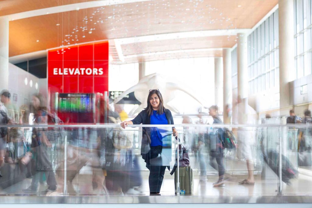 woman in airport with busy people behind her- tampa headshot photographer