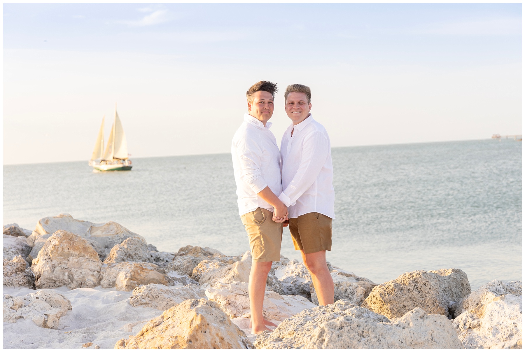 couple holding hands with sailboat in the back